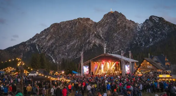 Tłumy ludzi na koncercie w Zakopanem pod oświetloną górą Giewont.