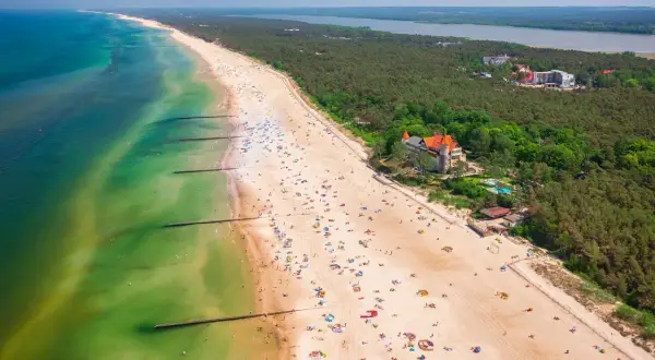 Widok z lotu ptaka na plażę w Łebie z turystami, morzem i lasem.
