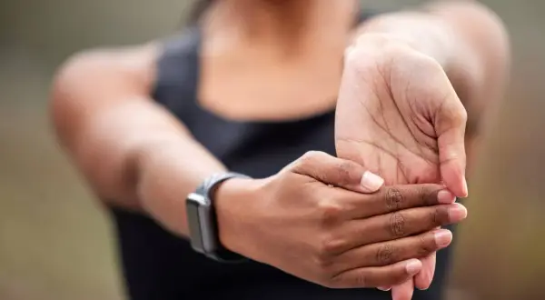Une personne étire son poignet, peut-être pour soulager une douleur tendon poignet après un effort.