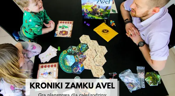 Rodzina gra w "Kroniki zamku Avel". Plansza i elementy gry rozłożone na czarnym stole, dzieci i dorosły skupieni na rozgrywce.