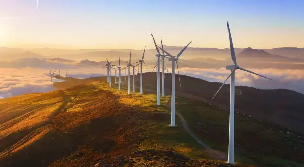 Wiatraki na wzgórzu o zachodzie słońca. Widać, jak działa turbina wiatrowa, łapiąc energię z wiatru.