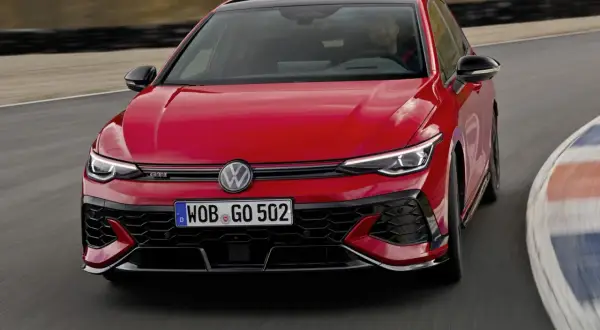 Czerwony Golf GTI Edition 50 na torze wyścigowym, z kierowcą za kierownicą, gotowy do ostrej jazdy.