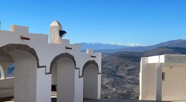 Arcos blancos y un paisaje montañoso nevado en la sierra de Almería bajo un cielo azul.