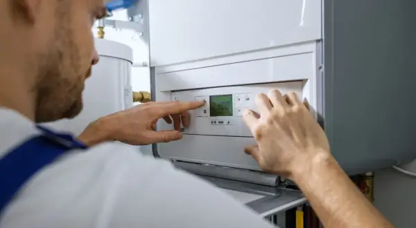 Fachowiec ustawia piec gazowy, co jest kluczowe dla kosztu instalacji gazowej w domu.