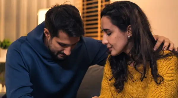 Een man met zijn arm om de schouder van een vrouw. Ze zitten dicht bij elkaar, wat hoop geeft op de kans van slagen relatie na vreemdgaan.