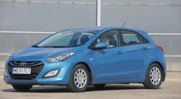 Niebieski Hyundai i30, gotowy do jazdy dziennej. Kierowca w okularach siedzi za kierownicą.
