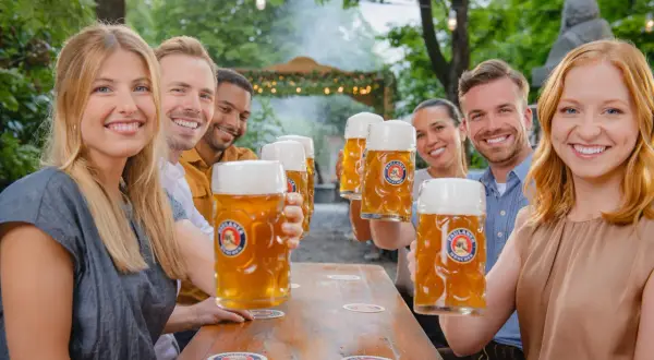 Freunde stoßen mit großen Krügen unfiltriertes Bier an.