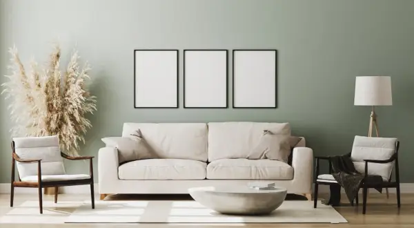 Miętowa ściana idealnie komponuje się z białymi meblami, tworząc przytulną aranżację. Sofa, fotele i stolik kawowy w jasnych barwach.