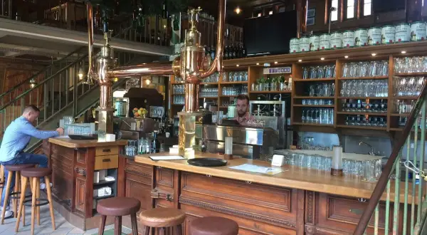 Gemütliche Atmosphäre im Brauhaus Spandau. Ein Mann sitzt am Tresen, hinter ihm Regale voller Gläser und Bierfässer.