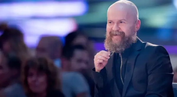 Alexander Bard, med sitt karaktäristiska skägg och skalliga huvud, ler och gestikulerar under ett event.