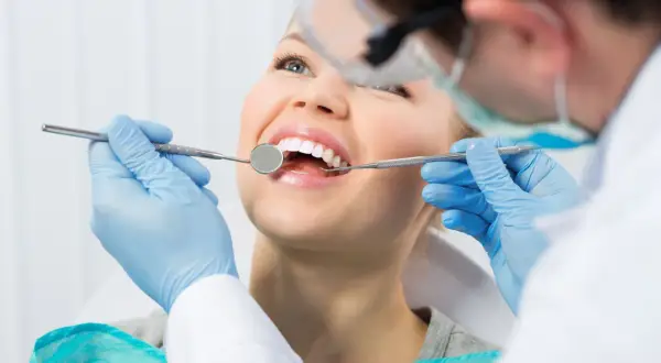 Uśmiechnięta pacjentka u dentysty. Zastanawiasz się nad lakowaniem zębów? Skutki uboczne są rzadkie, ale warto wiedzieć.