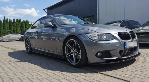 Szare BMW E92 335d z przyciemnianymi szybami i sportowym dyfuzorem, zaparkowane na zewnątrz.