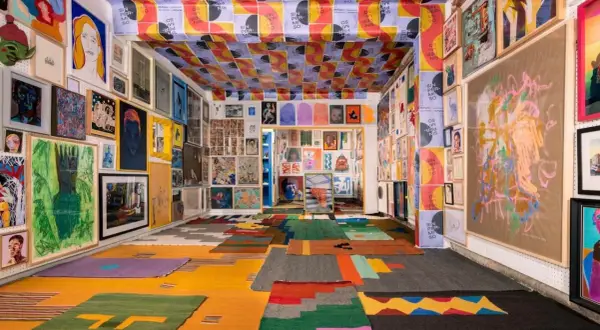 Vibrant art fills a room, from the ceiling posters to the floor rugs, showcasing the diverse creativity of Mexico City Art Week.