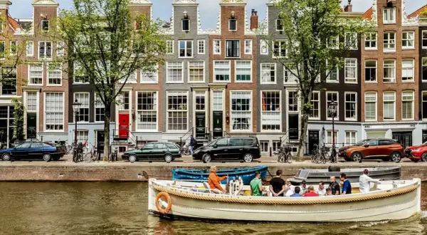 En båttur på kanalerna är ett måste i Amsterdam. Vackra hus och träd kantar vattnet.