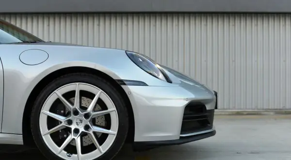 Srebrny Porsche 911 Carrera 4S z felgami i zaciskami hamulcowymi.