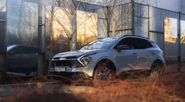 Nowy kia crossover odbija się w lustrzanych panelach, tworząc surrealistyczny krajobraz miejski.