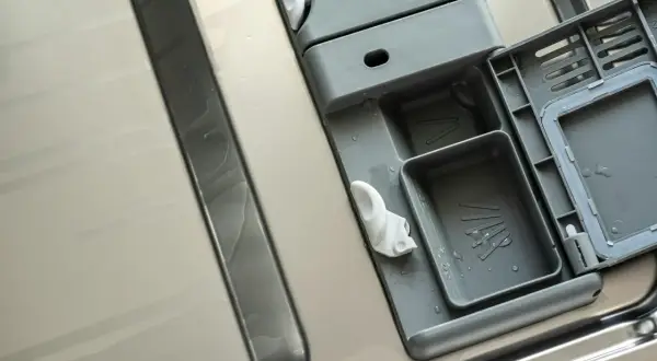 Wnętrze zmywarki Whirlpool po czyszczeniu. Widoczny dozownik na detergenty i nabłyszczacz, gotowy do kolejnego cyklu.