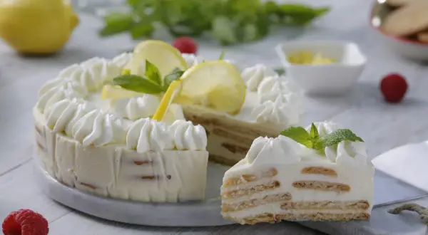Delicioso pay de limón con capas de galleta y crema, decorado con rodajas de limón y menta.