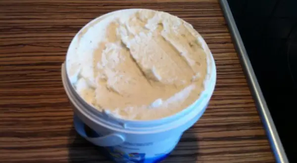 Ein Behälter mit cremigem, selbstgemachtem laktosefreiem Eis steht auf einer Holzoberfläche.
