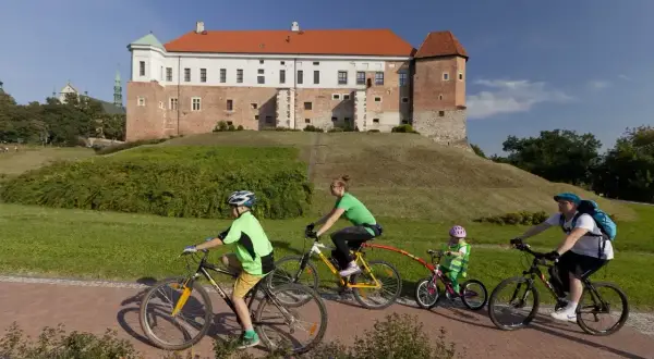 Rodzina na rowerach odkrywa sandomierskie trasy rowerowe z widokiem na zamek.