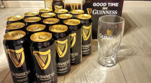 Dużo puszek Guinness z złotymi wieczkami i pustą szklanką, gotowe na dobrą zabawę z Guinness.