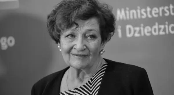 Uśmiechnięta Ewa Dałkowska, z perłami w uszach, na tle napisu "Ministerstwo i Dziedzictwo".