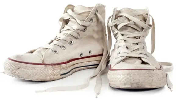 Zwei abgetragene, weiße Chucks mit Schnürsenkeln, bereit zum Chucks waschen.
