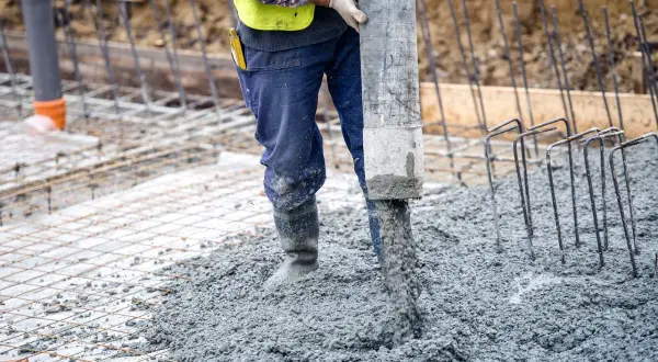 Robotnik wylewa beton na zbrojenie. Różne rodzaje betonu są kluczowe dla wytrzymałości konstrukcji.