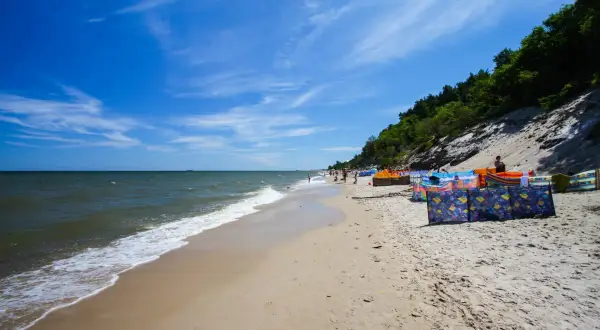 Słoneczna plaża w Chłapowie z kolorowymi parawanami, idealna na rodzinne wakacje. Atrakcje dla dzieci czekają!