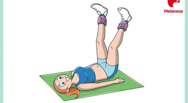 Donna con pesi alle caviglie esegue un esercizio per gli adduttori a terra, sollevando le gambe.