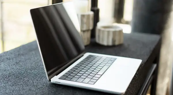 Nowy laptop czeka na pierwsze uruchomienie. Na blacie obok stoją ozdobne świeczniki.