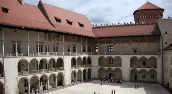 Dziedziniec zamku królewskiego na Wawelu, z arkadowymi krużgankami i wieżą. Ciekawostki o historii tego miejsca czekają na odkrycie.