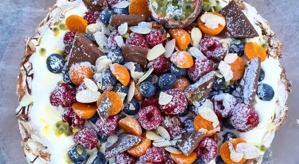 En härlig pavlova tårta fylld med färska bär, passionsfrukt, choklad och mandel.