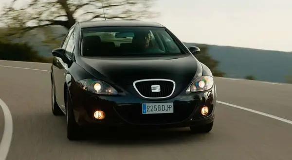 Czarny Seat Leon 2 z 2006 roku na zakręcie drogi.
