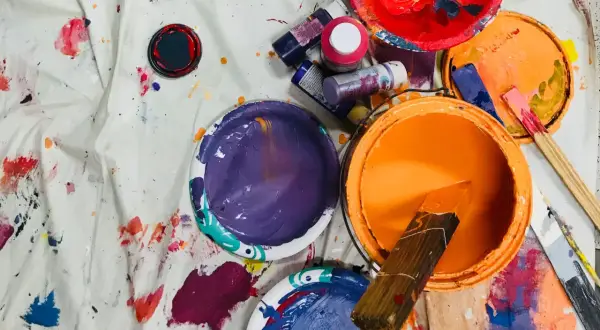 Pots de peinture acrylique ouverts, éclaboussés sur une toile. La durée conservation peinture acrylique dépend de son stockage.