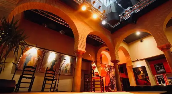 Escenario listo para la gracia flamenca. Sillas, guitarras y cuadros evocan la pasión del arte.