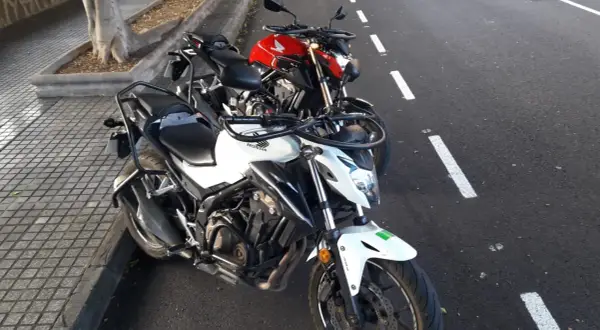 Dos motos Honda, una blanca y otra roja, aparcadas en la calle. ¿Listo para obtener tu carnet a como sacarlo?
