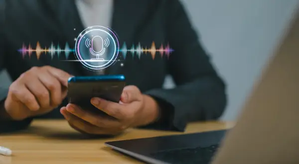 Osoba korzysta z telefonu, na ekranie widoczny jest symbol mikrofonu i wizualizacja dźwięku. Dowiedz się, jak nagrać rozmowę telefoniczną.