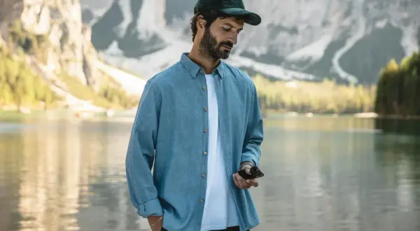 Un homme porte une chemise bleue décontractée, dont la matière légère est parfaite pour une journée au bord du lac.