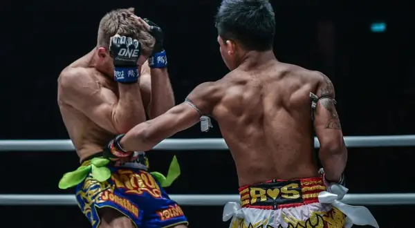 A Muay Thai fighter lands a powerful uppercut, connecting with his opponent's chin. The shovel hook defense is too late.