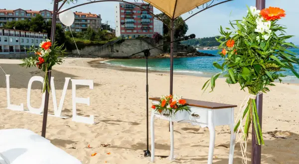 Decoración de boda en la playa de lagos Bueu: letras "LOVE", mesa de altar, flores y el mar azul.