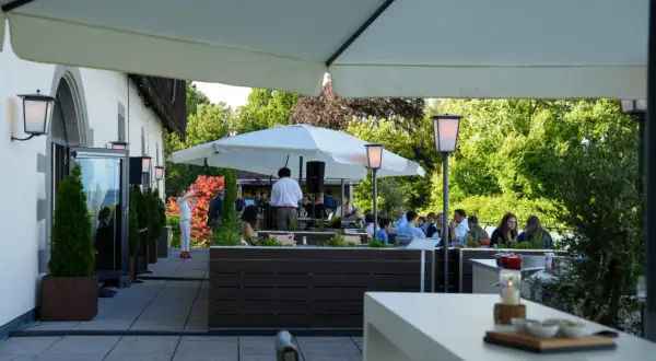 Gäste genießen den Abend im **Haigern Restaurant** auf der Terrasse unter Sonnenschirmen, mit grünen Bäumen im Hintergrund.