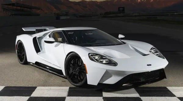 Biały Ford GT na torze wyścigowym, z górami w tle. Marzenie o osiągach i stylu, które wpływa na ford gt cena.
