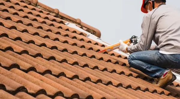 Handwerker repariert die Dachrinne mit einer Kartuschenpistole.