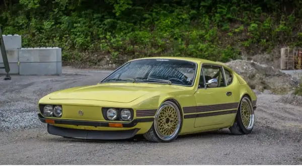 Gul vw sp2 med guldfärgade fälgar står på grusväg.