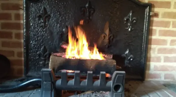 Un feu crépite dans une cheminée en briques, avec un système discret pour récupérer la chaleur d'un conduit de cheminée.