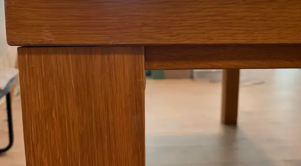 Detaljbild av ett träbord i fanér, redo för renovering.