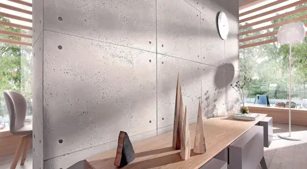 Nowoczesna ściana z betonu architektonicznego, inspiracja jak kłaść beton dekoracyjny na ścianę. Drewniane dekoracje i światło tworzą przytulną atmosferę.