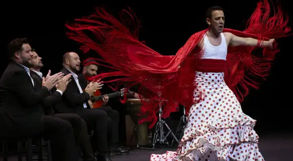 Antonio, cantante flamenco, baila con pasión, su mantón rojo ondea mientras los músicos le acompañan.