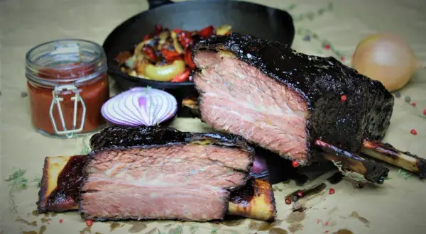 Zart geschmorte short ribs, glasiert und saftig, mit Beilagen wie Zwiebeln und Sauce.